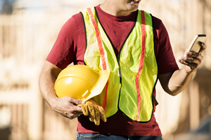 man in yellow vest holding hard hat